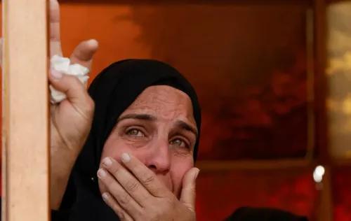 امرأة ترتدي الحجاب، تبكي بحرقة، تعبر عن ألمها ومعاناتها في ظل الظروف الصعبة في غزة. تعكس الصورة واقع النزاع المستمر والأثر على المدنيين.