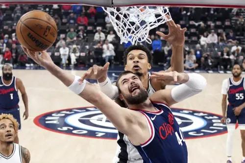 لاعب كليبرز إيفيكا زوباك يسجل نقطة تحت الضغط من لاعب سبيرز، مع تواجد الجمهور في الخلفية.