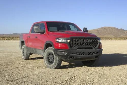 شاحنة فورد F-150 رابتر R الحمراء، مصممة للطرق الوعرة، مع محرك V8 سوبرتشارجد بقوة 720 حصاناً، على أرض رملية في منطقة جبلية.