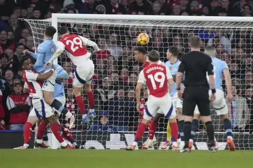 جابرييل مدافع أرسنال يتصدى لإرلينغ هالاند مهاجم مانشستر سيتي خلال مباراة مثيرة في الدوري الإنجليزي، مع احتفالات اللاعبين في الخلفية.