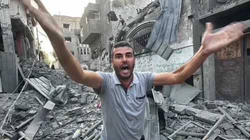 رجل يقف وسط أنقاض مباني مدمرة في غزة، يرفع ذراعيه ويعبر عن مشاعر قوية من الألم واليأس في ظل الظروف القاسية.