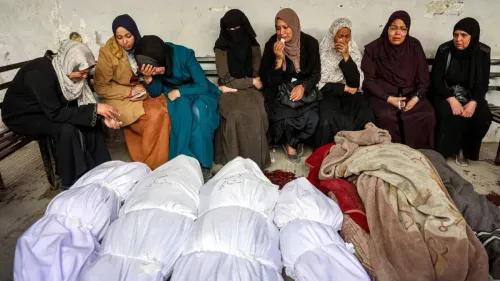 نساء يجلسن في حالة حزن، محاطات بجثث لأحبائهن، يعبرن عن ألم الفقد في سياق الأحداث المؤلمة في غزة.