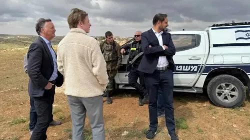 النائب البريطاني شوكت آدم يتحدث مع زملائه بالقرب من مركبة للشرطة الإسرائيلية في منطقة فلسطينية، وسط توتر سياسي.