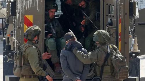 اعتقال فلسطيني من قبل جنود إسرائيليين، مع وجود مركبة عسكرية في الخلفية، في سياق تصعيد الاعتقالات بعد صفقة تبادل الأسرى.