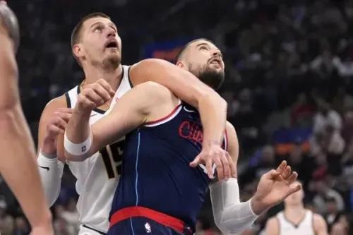 تظهر الصورة مواجهة بين نيكولا جوكيتش من دنفر ناجتس ولاعب لوس أنجلوس كليبرز، حيث يحاول كلاهما السيطرة على الكرة في مباراة بلاي أوف مثيرة.