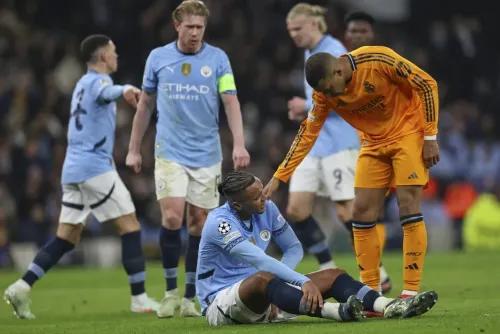 مدافع مانشستر سيتي مانويل أكانجي يجلس على الأرض مصابًا بعد مباراة ضد ريال مدريد، بينما يتواصل معه لاعب من الفريق المنافس.