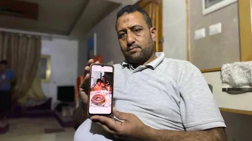 والد نوح السقا يحمل هاتفه الذكي الذي يظهر صورة لابنه نوح يحتفل بعيد ميلاده مع كعكة بسيطة، وسط أجواء من الحزن بسبب الظروف الصعبة في غزة.