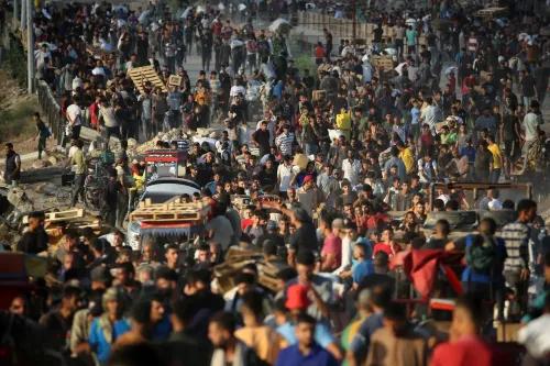 ازدحام كبير من الناس في غزة يتجمعون حول مراكز الإغاثة، مع ظهور أكياس الطحين في الخلفية، في ظل أزمة إنسانية متزايدة.