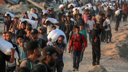 مئات الفلسطينيين في غزة يحملون أكياس المساعدات الغذائية، في ظل ظروف خطيرة وقيود مشددة، بحثًا عن الغذاء وسط الصراع.
