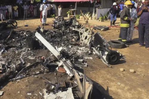 حطام طائرة خفيفة محترقة في بلدة كواتشوشا بكينيا، مع وجود رجال إطفاء ومشاهدين في الخلفية، بعد حادث مأساوي أسفر عن وفيات.
