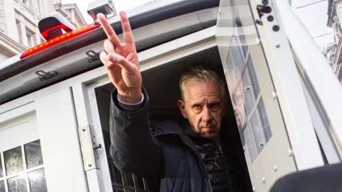 ناشط مؤيد لفلسطين يظهر من سيارة الشرطة، مشيراً بعلامة النصر، وسط تجمعات تضامنية خارج محكمة ويستمنستر.