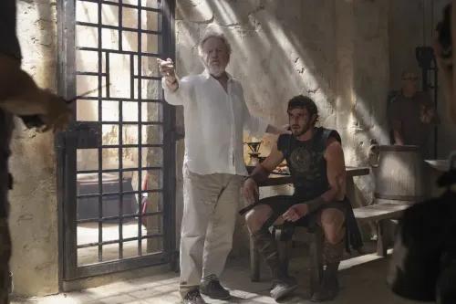 ريدلي سكوت يوجه بول ميسكال في مشهد من فيلم \"Gladiator II\"، في موقع تصوير يبدو كغرفة تاريخية.