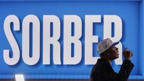 لاعب كرة سلة شاب يرتدي قبعة تحمل اسم "SORBER" ويشير بإيماءة إيجابية، خلفه لافتة كبيرة تحمل نفس الاسم.