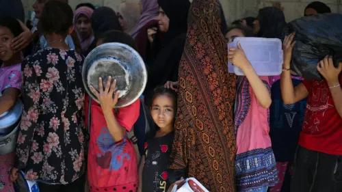 طفلة فلسطينية تنظر بقلق بينما تنتظر عائلتها في طابور للحصول على المساعدات الغذائية في غزة، وسط ظروف إنسانية صعبة.