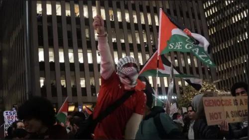 متظاهر يحمل لافتة ويرتدي كوفية فلسطينية، محاطًا بأعلام فلسطينية، في احتجاج ضد الانتخابات الأمريكية في نيويورك.