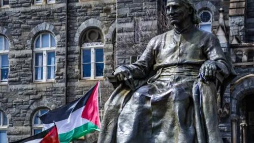 تمثال برونزي لشخصية تاريخية جالس أمام مبنى حجري، مع وجود علم فلسطين يرفرف بجانبه، مما يعكس سياق القضايا المتعلقة بفلسطين.