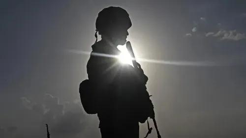 جندي يقف silhouetted أمام الشمس، مما يرمز إلى التوترات العسكرية بين الهند وباكستان في كشمير، وسط تصاعد النزاع.