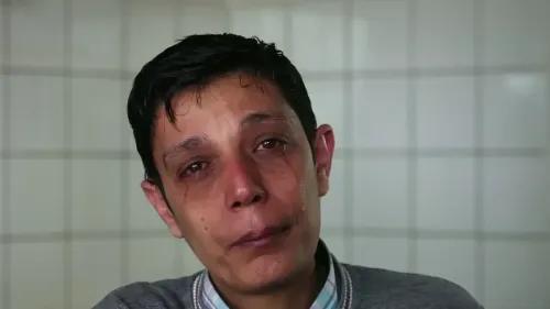 شاب سوري يبكي بحرقة، معبرًا عن مشاعر الحزن والأسى، في خلفية بيضاء، يعكس معاناته كلاجئ في ظل نظام الأسد.