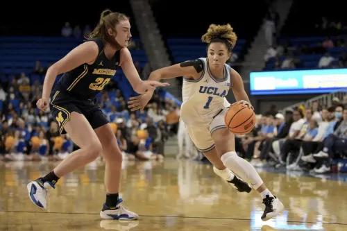 لاعبة كرة سلة من فريق جامعة كاليفورنيا في لوس أنجلوس (UCLA) تتجاوز لاعبة من فريق ميشيغان، بينما يتابع الجمهور المباراة في بولي بافيليون.